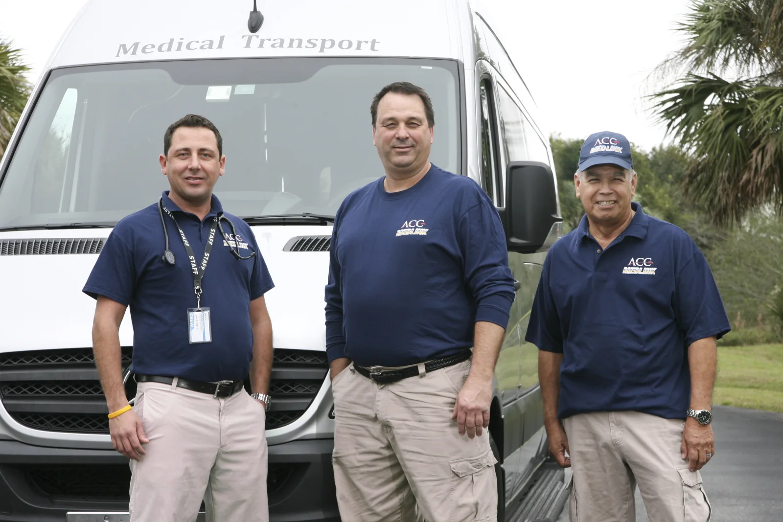 Three ACC Medlink crew members in company polos in front of a Sprinter van
