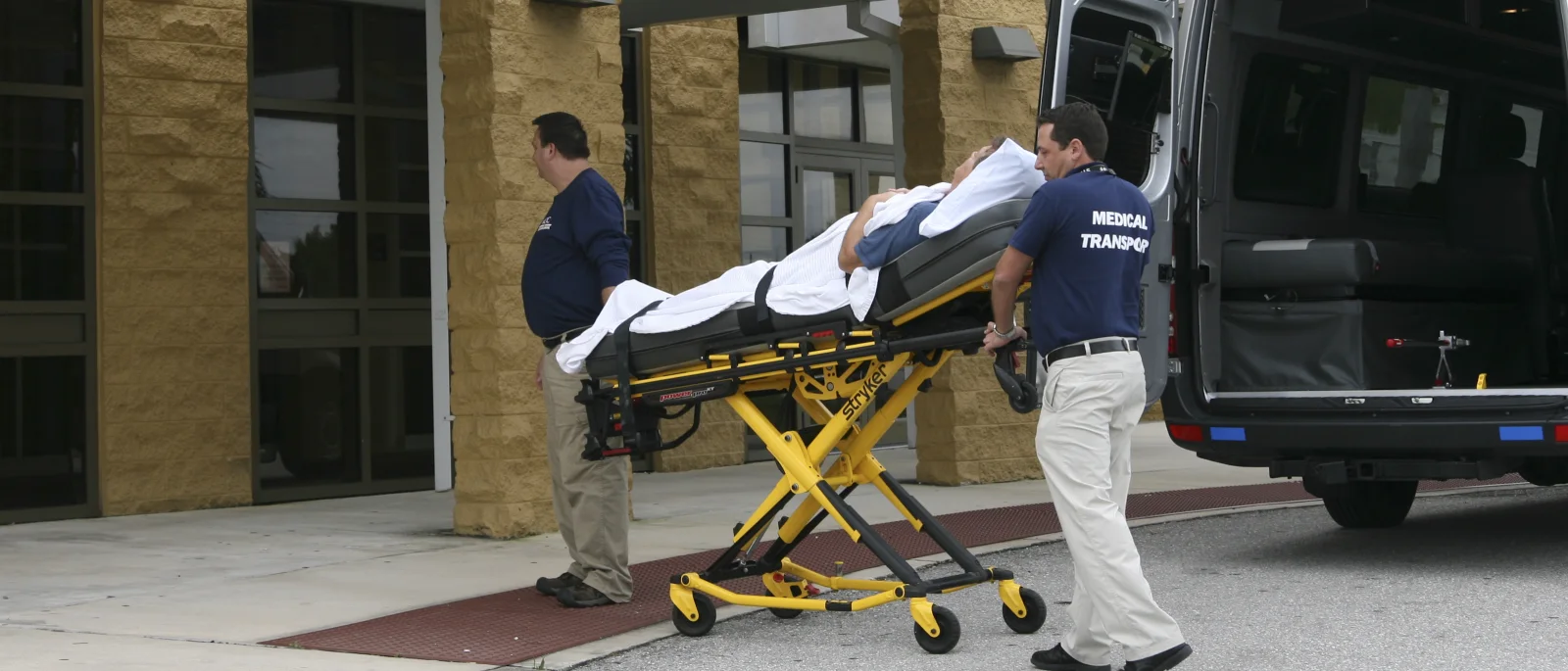 ACC Medlink crew wheeling a patient on a stretcher to the transport van