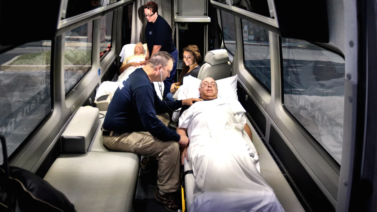 ACC Medlink medical professional caring for a patient in a bed inside a Sprinter, with family seated nearby