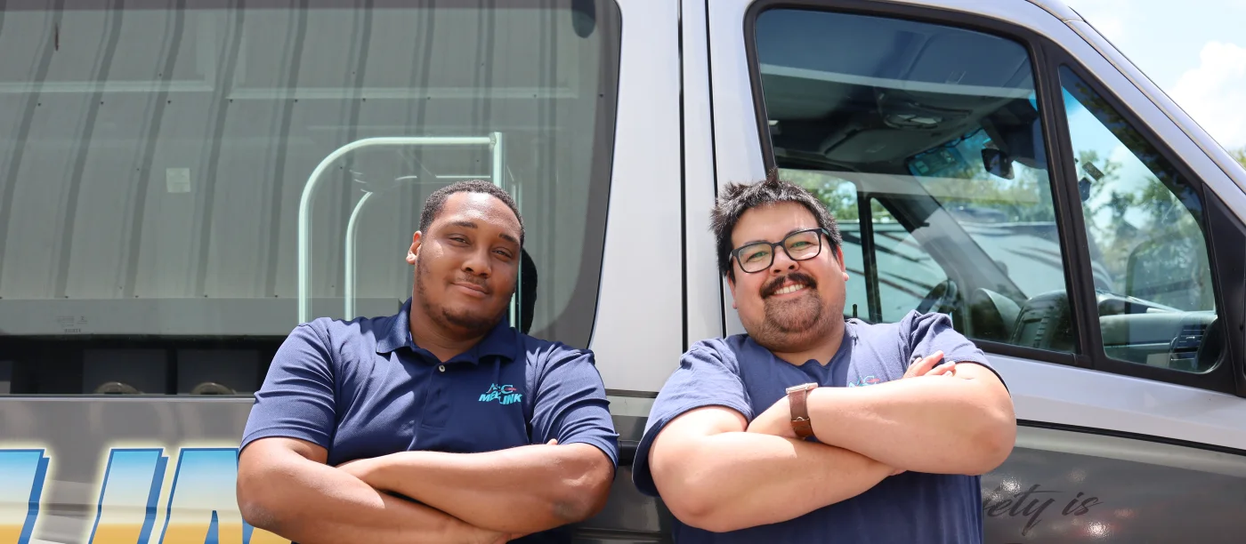 Two ACC Medlink crew members standing in front of their Sprinter transport van