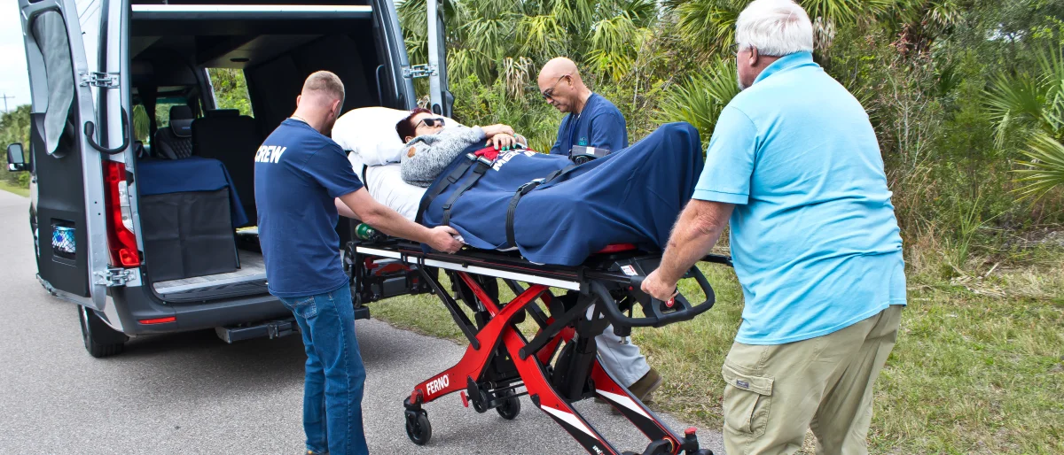 ACC Medlink crew and a family member loading a patient on a stretcher into the back of a Sprinter