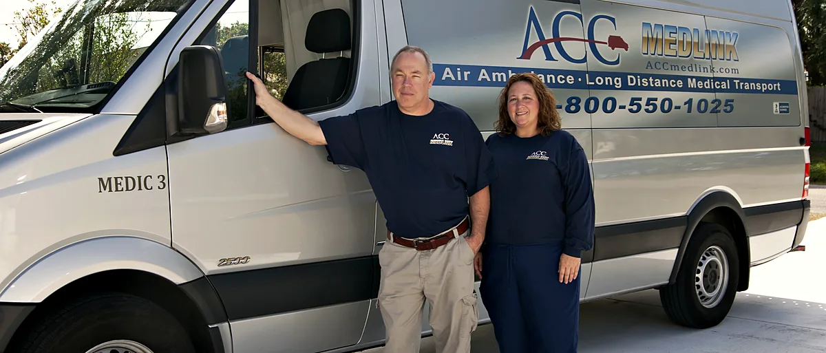 Two ACC Medlink crew members standing beside their Sprinter transport van