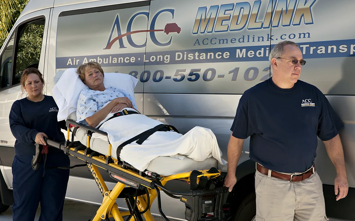 ACC Medlink crew with a patient on a stretcher beside an ACC Medlink transport van