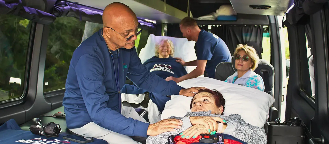 ACC Medlink medical attendant caring for a patient in a bed while a family member rides along