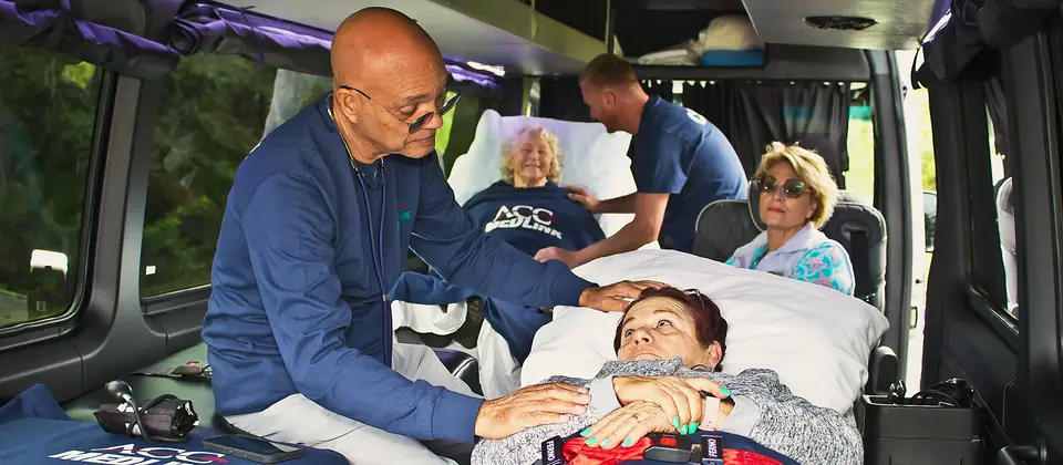 ACC Medlink medical attendant caring for a patient in a bed while a family member rides along