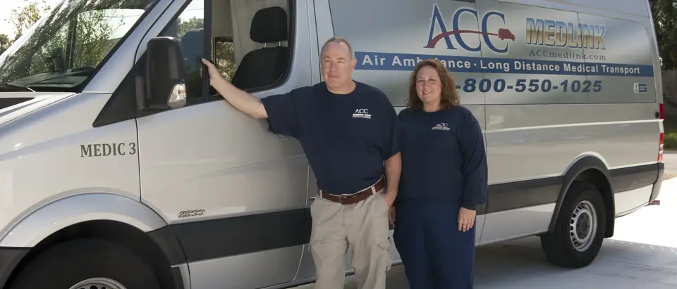 Two ACC Medlink crew members standing beside a Sprinter transport van