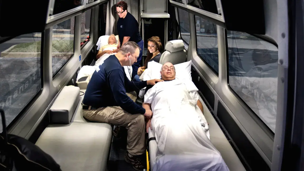 ACC Medlink medical professional caring for a patient in a bed inside a Sprinter, with family seated nearby